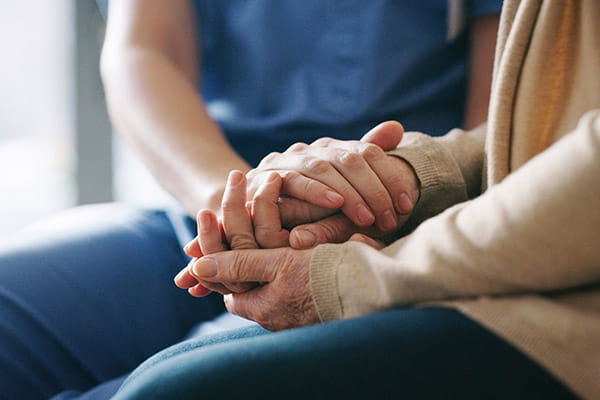 a close-up of the hands of a healthcare professional comforting a senior woman
