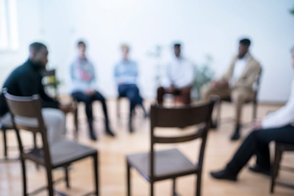 blurred group of people sitting on chairs in a circle