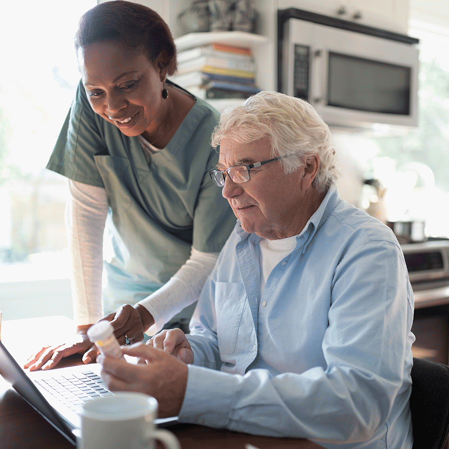 A healthcare worker and her patient are looking at a laptop.