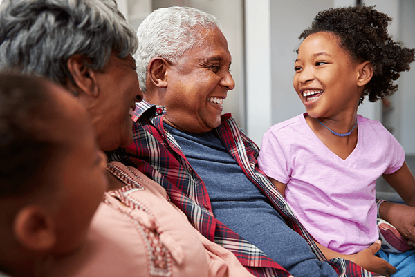 grandparents relaxing on sofa at home with grandchildren