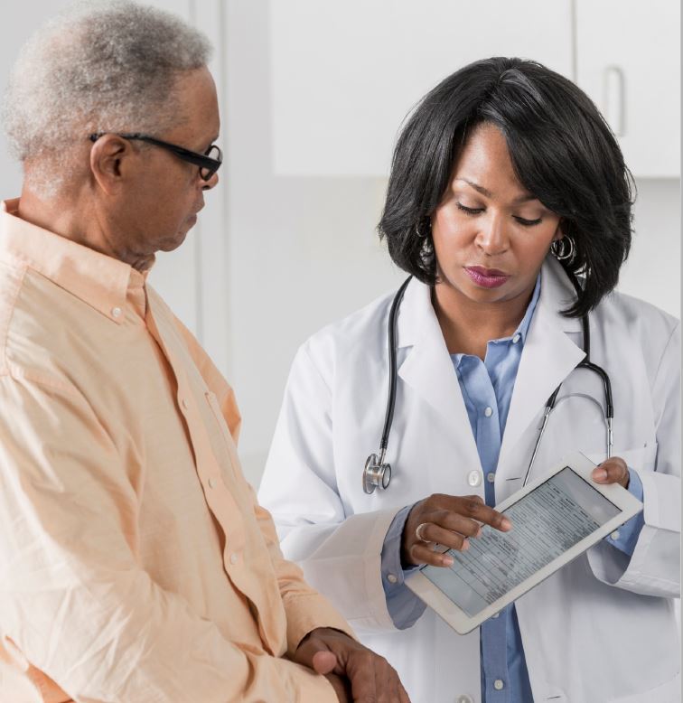 A doctor is showing information on a tablet to her senior male patient.