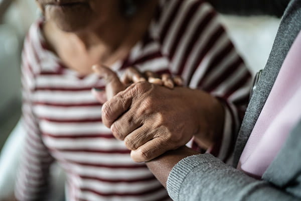 caregiver holding a senior woman's hand to provide support