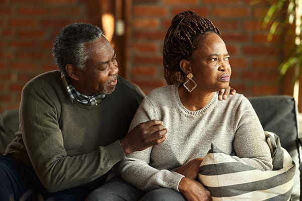 Displeased Black mature woman is ignoring her husband who is talking to her in the living room.