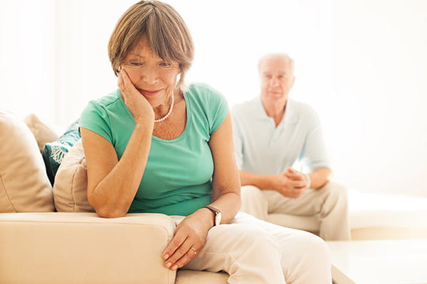 Senior woman upset while concerned husband looks on