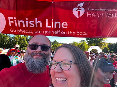 Stroke survivor Chris Rose and his wife under a Heart Walk finish line banner