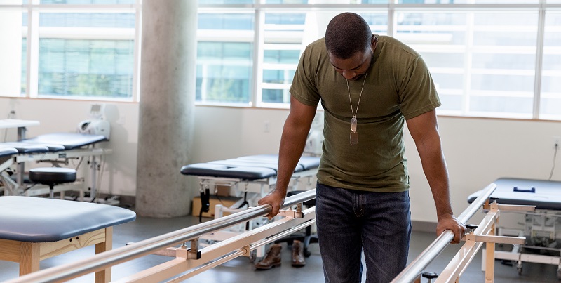 Man using bars to walk as a part of rehab