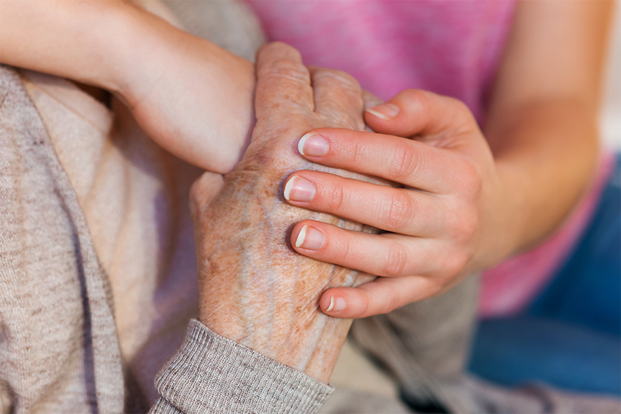 Senior woman and younger child clasped hands