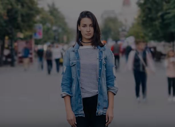 Woman standing still with a crowd of people walking around her