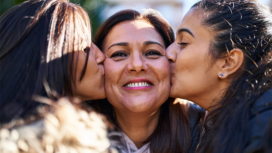 Daughters kissing their mother on the cheek