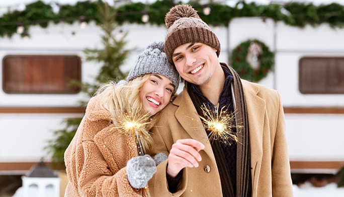 Man and woman holding fire sparklers outside in the snow