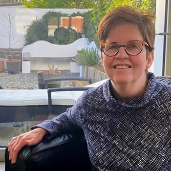 Kathy O’Leary is sitting in a chair in front of a window Kathy O’Leary is sitting in a chair in front of a window