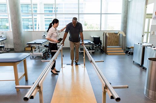 Caring female physical therapist helps stroke victim in rehab center