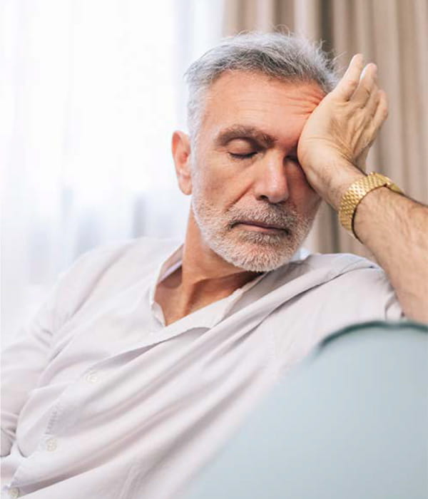 Older man with closed eyes and the palm of his hand on his forehead