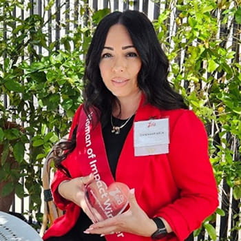 Dominica Padilla is wearing red and holding a crystal heart in an outdoor patio setting.