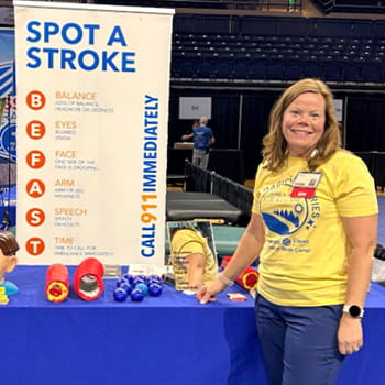 Julie Goins Whitmore is standing in front of her Spot a Stroke display table.