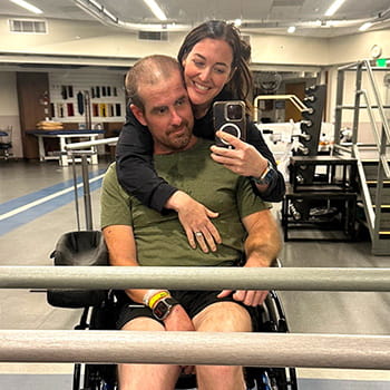 Stacie and Logan Barber taking a selfie in the gym mirror during physical therapy.