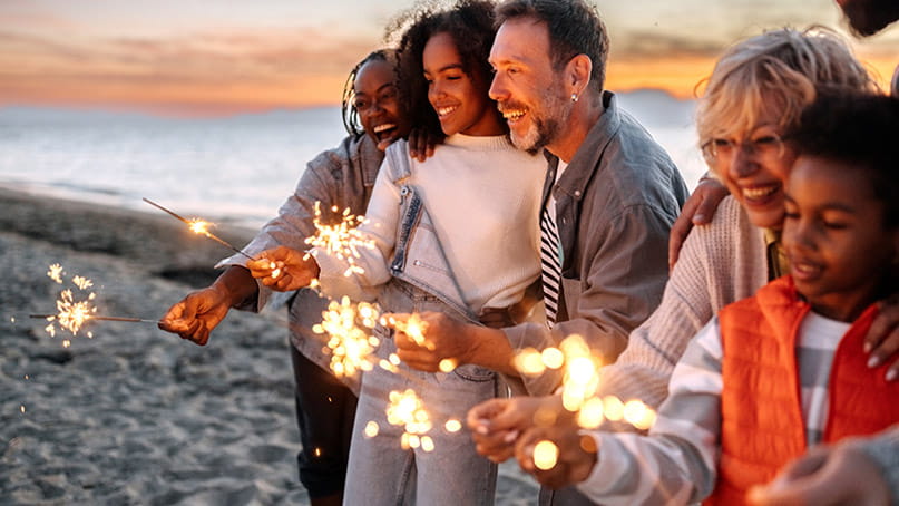 Multigenerational family with firework sparklers on the beach Multigenerational family with firework sparklers on the beach